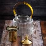 Luxury undulating glass teapot with gold accents and wooden handle